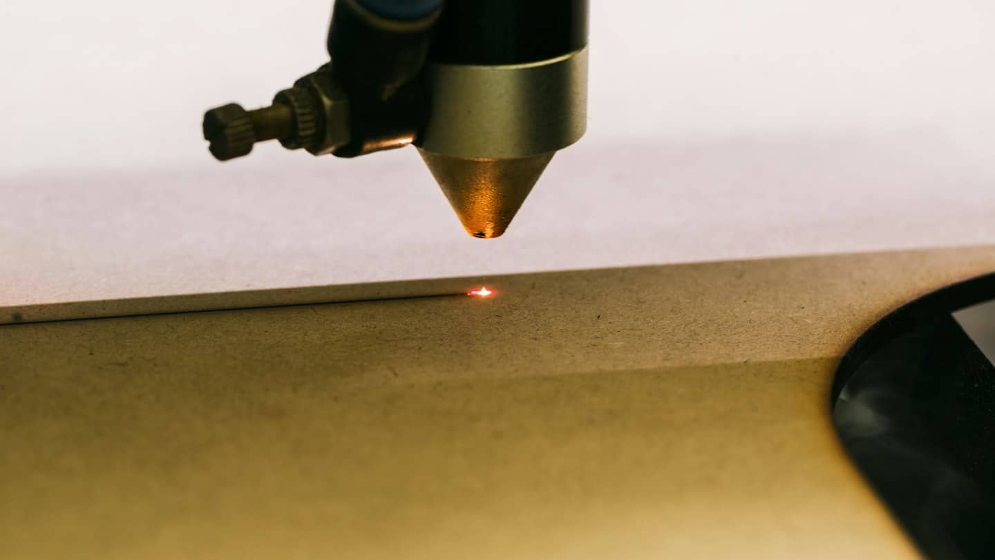 Laser engraver beam burning design into wood.