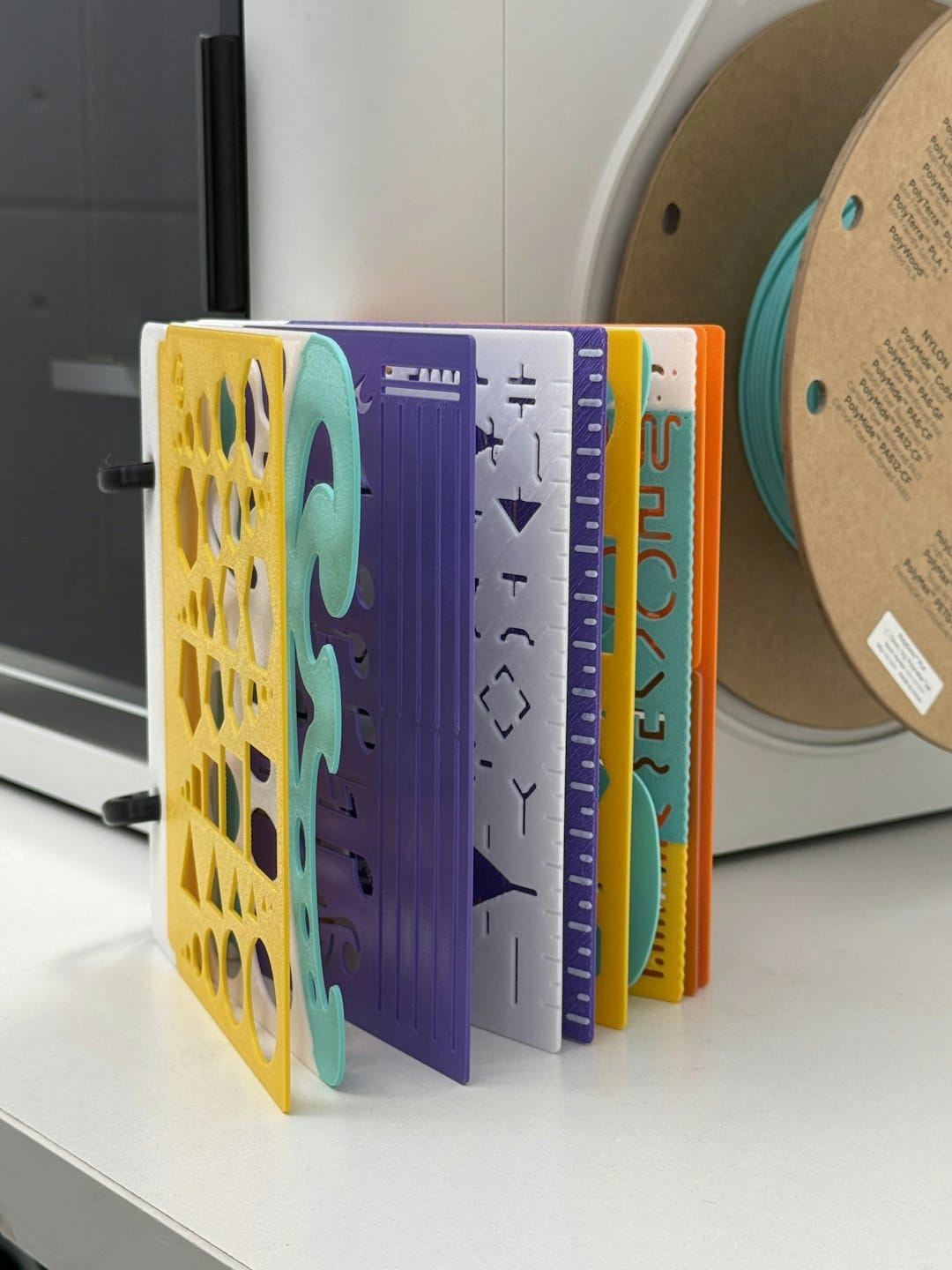 Colorful 3D printed stencils displayed like pages.