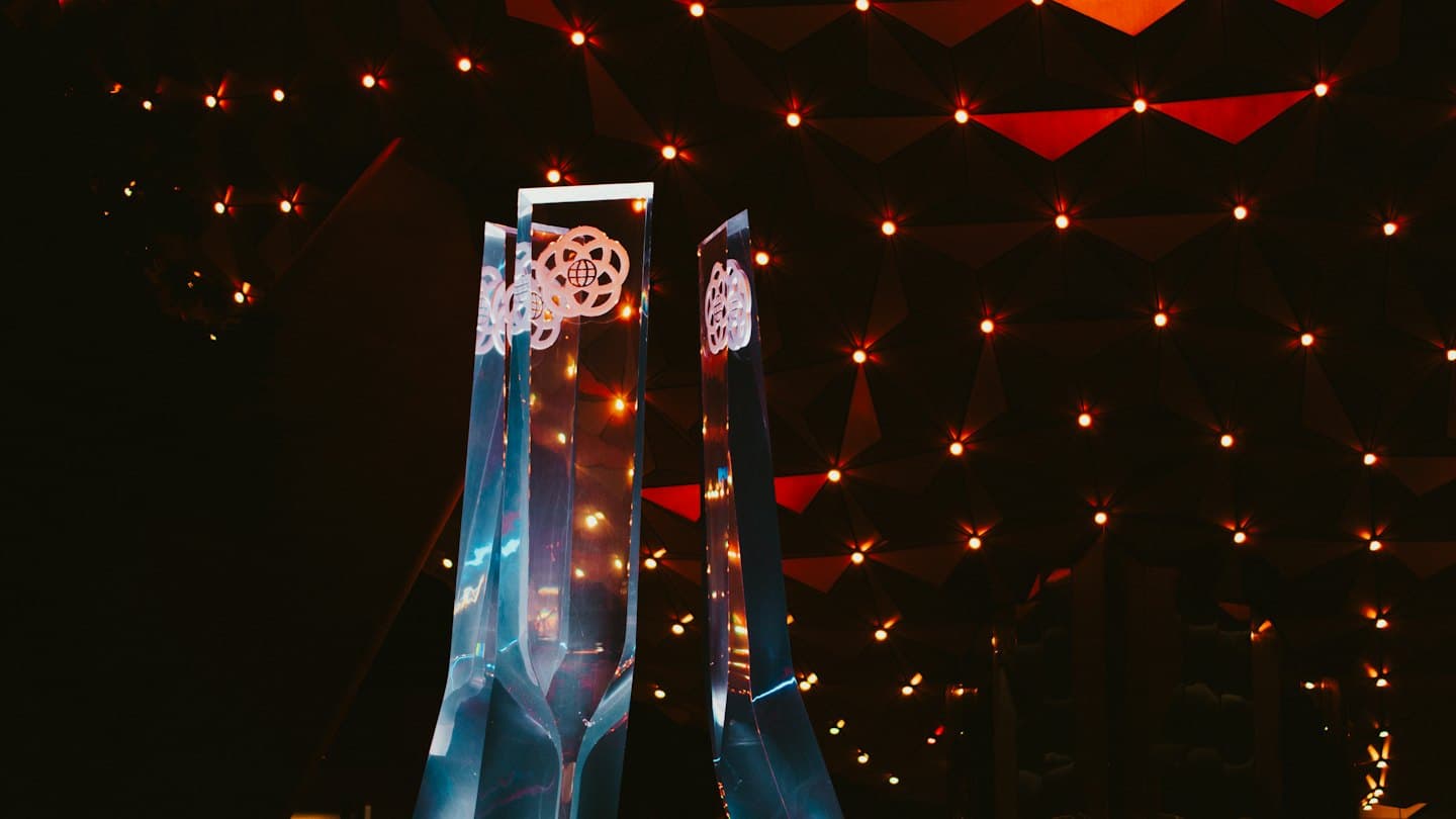 Two clear acrylic awards standing before a wall of lights.