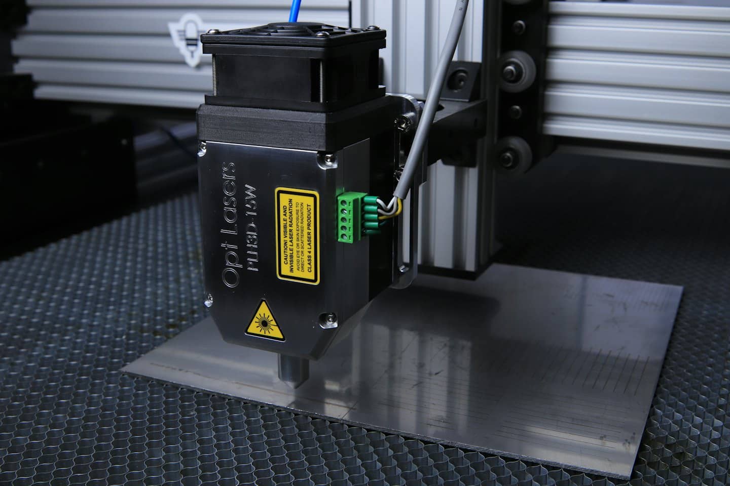 Laser engraver marking lines on brushed metal surface.